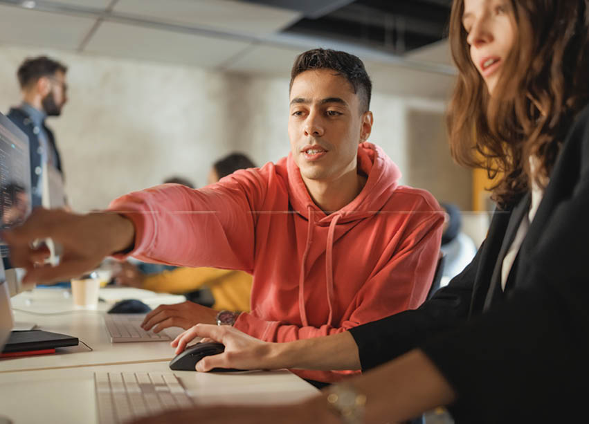 Diverse Multiethnic Group of Female and Male Students Sitting in College Room, Collaborating on School Projects on a Computer. Young Scholars Study, Talk, Apply Academic Skills and Knowledge in Class.